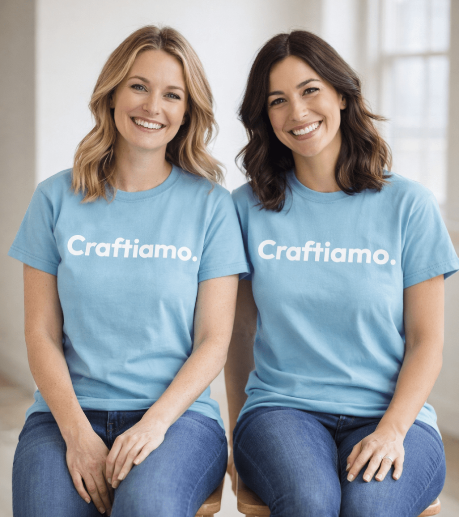 due donne sorridenti, una biona e una mora, sedute su uno sgabello in legno. Indossano una maglietta celeste con il logo craftiamo in bianco