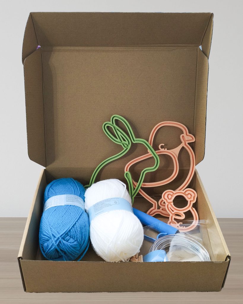 kit per ambassador Craftiamo con telai filoforma in una scatola di cartone insieme a gomitoli di lana