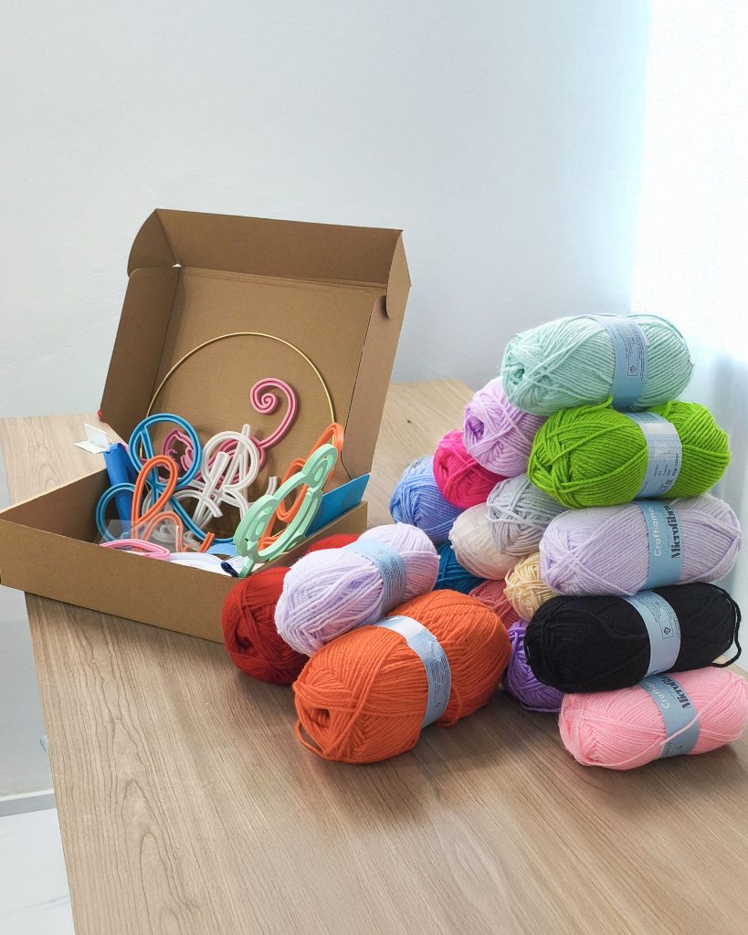 kit per ambassador Craftiamo con telai filoforma in una scatola di cartone insieme a gomitoli di lana