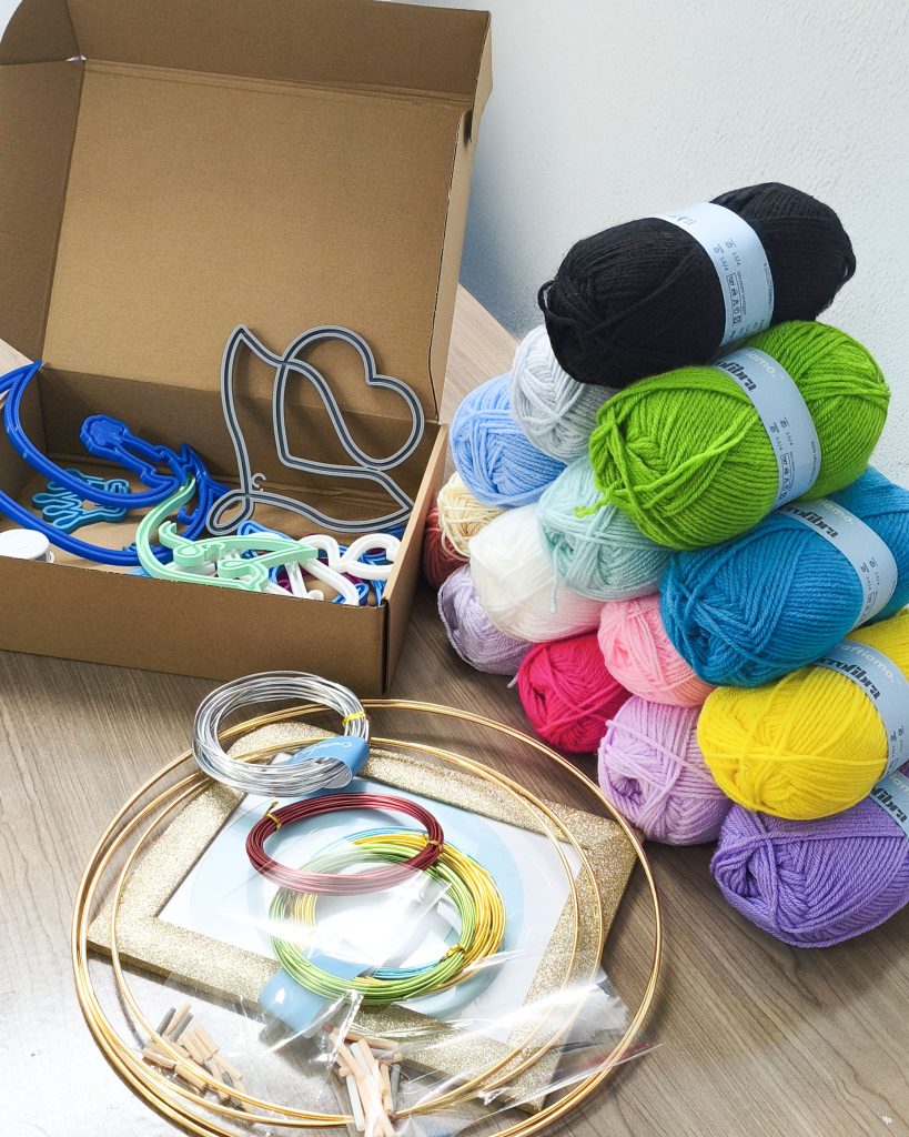 kit per ambassador Craftiamo con telai filoforma in una scatola di cartone insieme a gomitoli di lana
