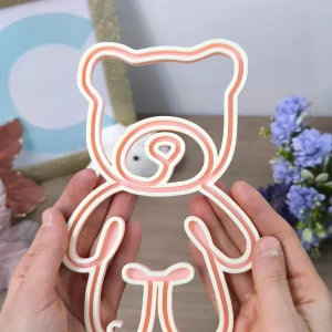 Telaio FiloForma a forma di orso in colore rosa tenuto fra due mani su sfondo chiaro