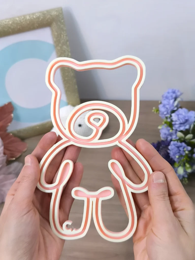 Telaio FiloForma a forma di orso in colore rosa tenuto fra due mani su sfondo chiaro