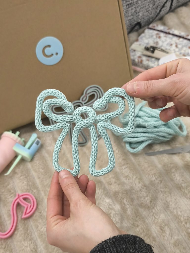 Fiocco realizzato a tricotin in cotone verde chiaro tenuto in mano