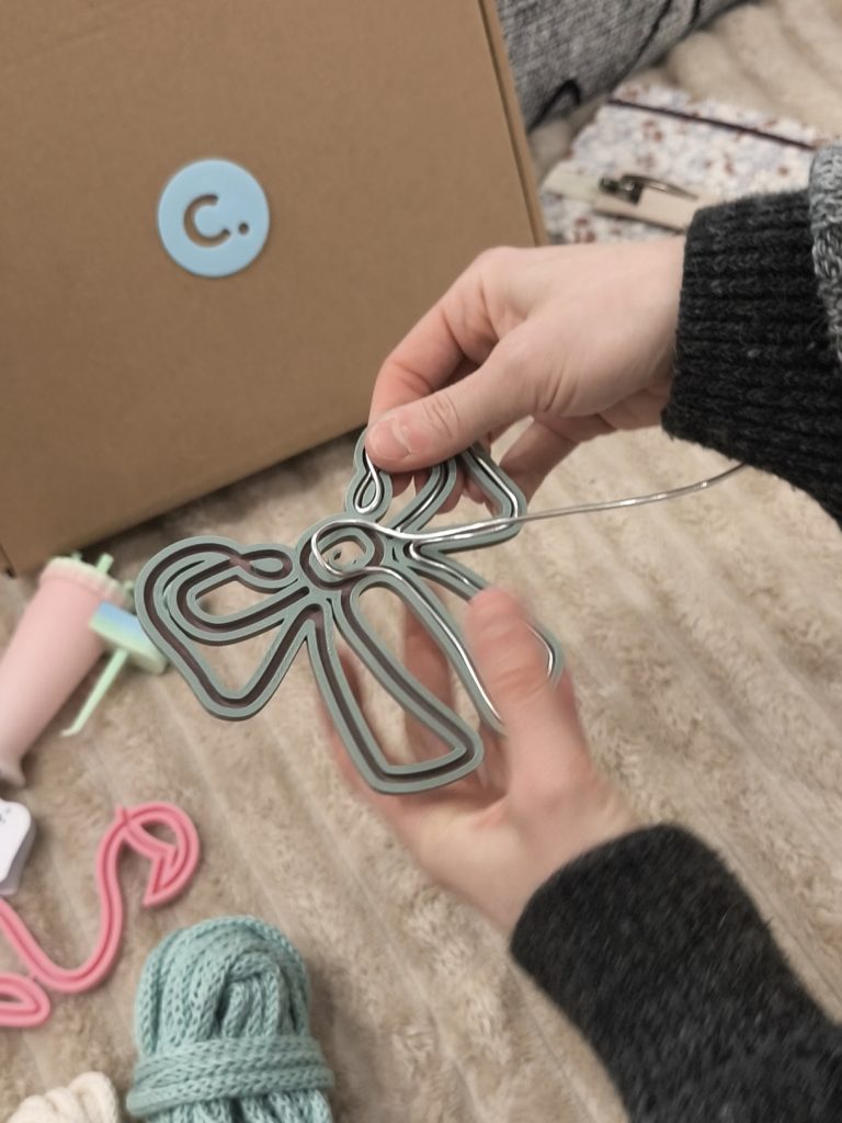 telaio filoforma tenuto in mano mentre l'altra mano modella al suo interno il filo di alluminio